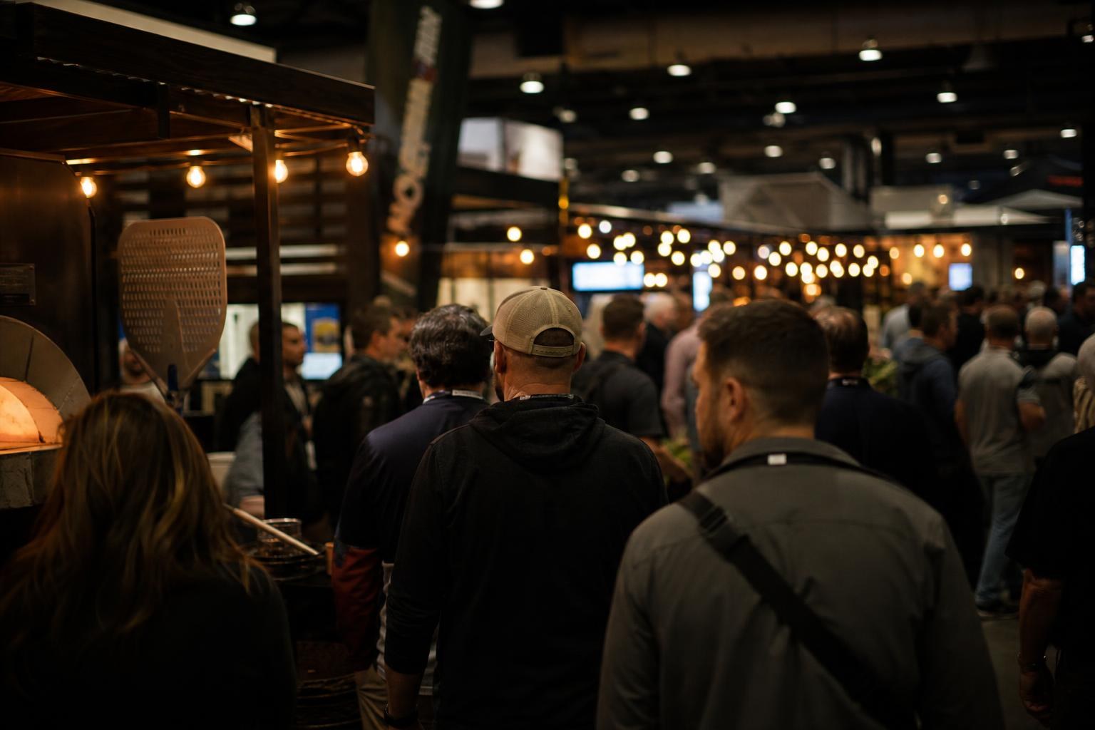 Attendees move between glowing booths at a pizza industry trade show