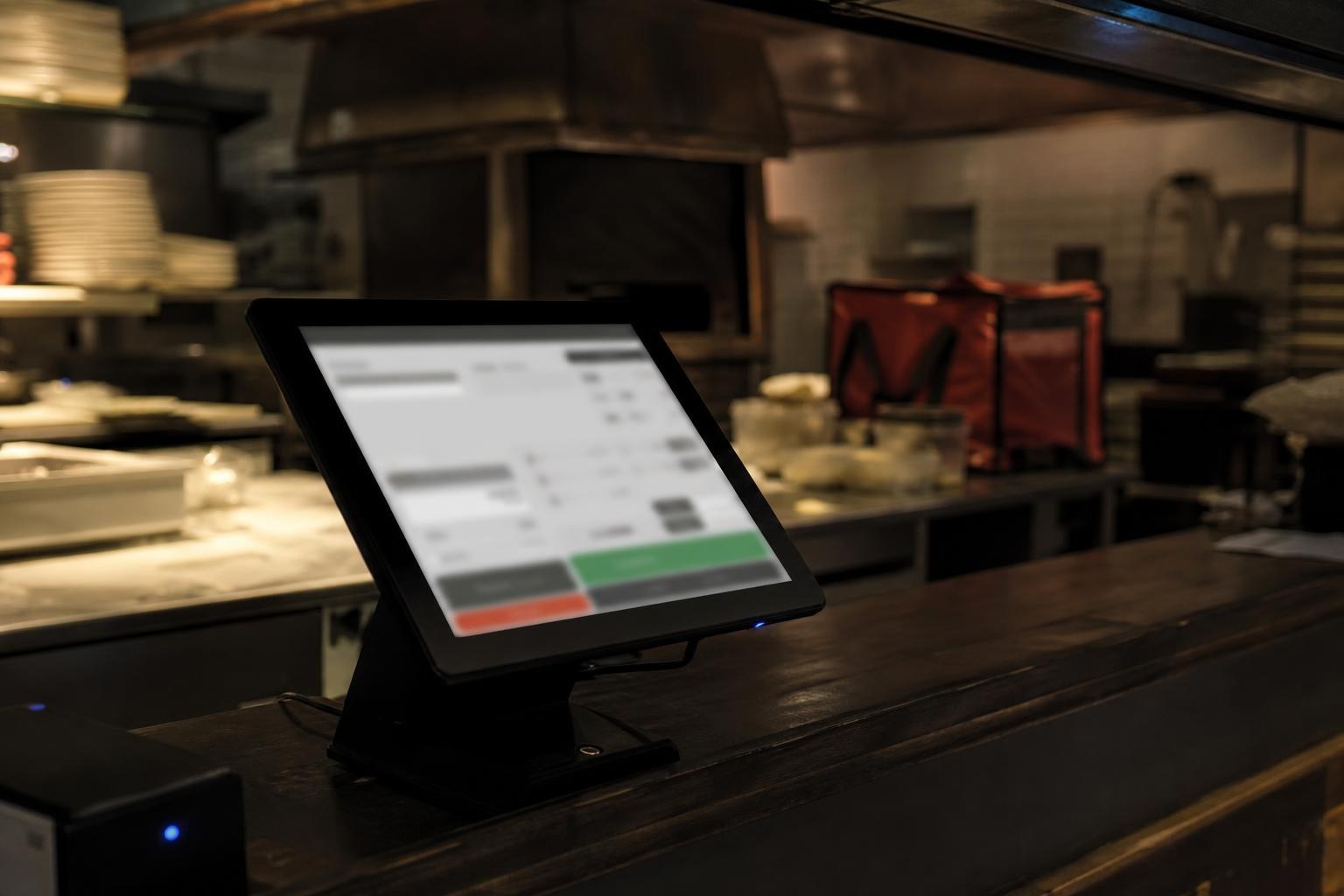 A point-of-sale touchscreen glowing on a dark pizzeria counter